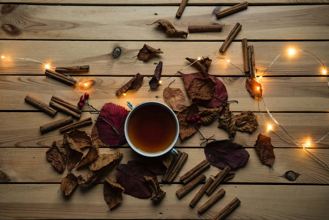 Cup of hot herbal tea surrounded by autumn leaves.